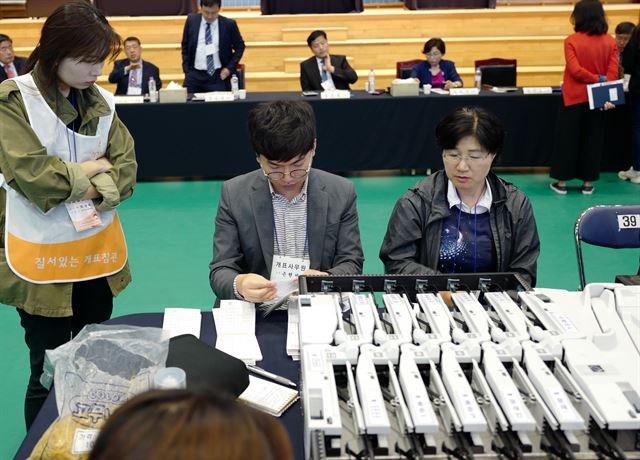 한국일보 손현성 기자(가운데)가 9일 오후 경기 과천시 청소년수련관에서 대선 개표사무원으로 참여해 참관인이 지켜보는 가운데 투표지 분류기를 통해 나온 표들을 묶고 확인하고 있다. 신혜정 기자.