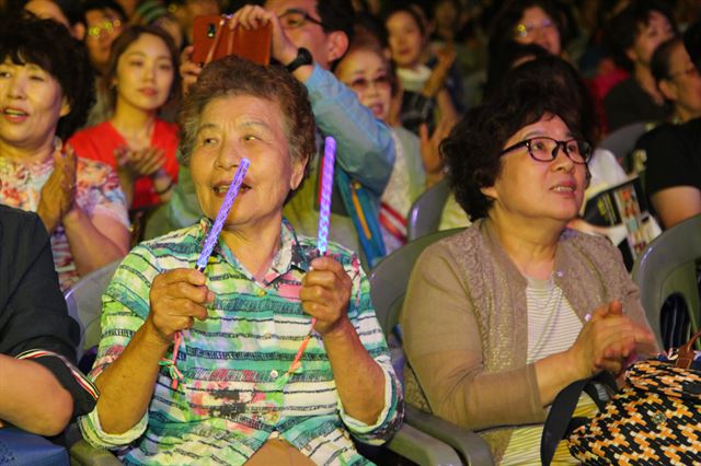 콘서트 중 야광봉을 흔들며 가수를 공연을 즐기고 있는 어르신.