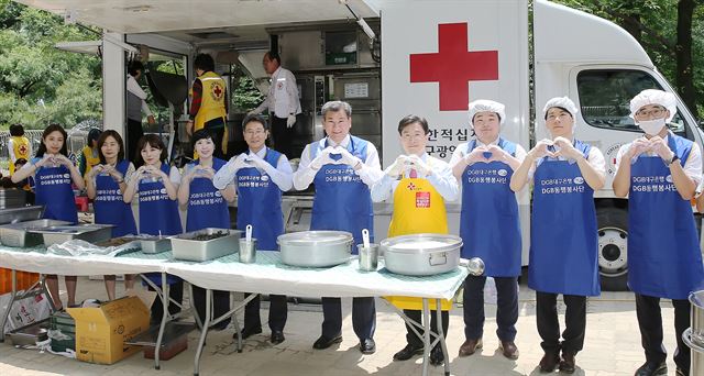 DGB대구은행 임직원과 대한적십자사 회원 등이 16일 대구 중구 달성공원무료급식소에서 배식봉사활동을 하고 두 손으로 사랑의 하트 표시를 하고 있다. 대구은행 제공