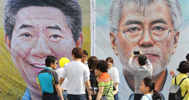 노무현 전 대통령 서거 8주기를 맞아 20일 오후 서울 광화문 광장에서 열린 시민문화제에 전시된 노 전 대통령과 문재인 대통령 초상화 앞에서 시민들이 기념사진을 찍으며 추억을 남기고 있다. 연합뉴스