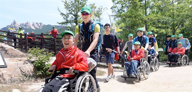 평소 휠체어 없인 보행이 어려운 마포장애인종합복지관 장애우들이 서울시산악연맹 소속 산악구조대원들의 도움으로 20일 오전 서울 북한산 우이령 둘레길에서 즐거운 산행을 하고 있다.배우한기자