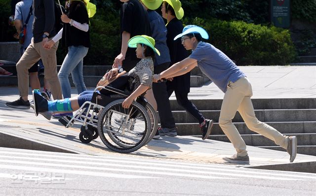 제465회 한국일보 거북이마라톤 '서울로 7017 보행길 개통 기념 걷기대회' 행사가 21일 오전 서울 남산 백범공원에서 열린 가운데 남편이 아내가 탄 휠체어를 밀며 행사장으로 향하고 있다. 홍인기 기자