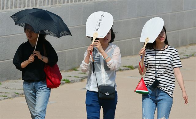 이른 무더위가 기승을 부린 지난달 30일 오후 서울 광화문 앞에서 시민들이 따가운 햇볕을 가리며 걷고 있다. 뉴시스