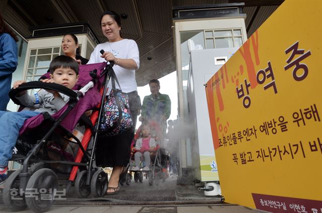 조류인플루엔자(AI)가 확산되고 있는 가운데 6일 경기도 과천 서울대공원을 찾은 관람객들이 입구에 설치된 대인 분무소독기를 지나고 있다. 서울대공원은 이날 AI 에방 차원에서 조류사의 운영을 중단했다. 신상순 선임기자ssshin@hankookilbo.com