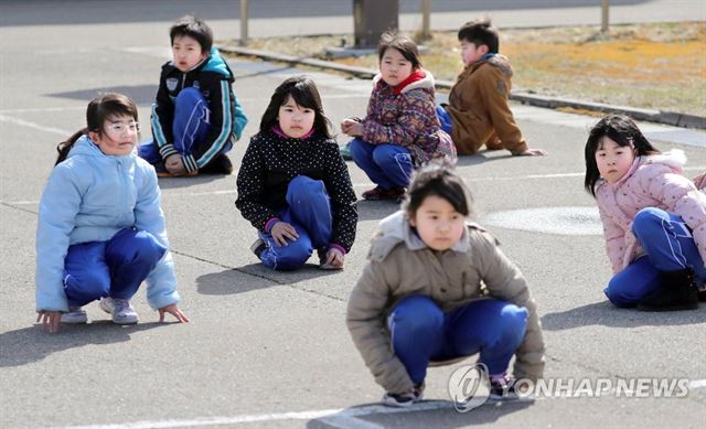 과거 아키타(秋田)현 오가(男鹿)시에서 진행된 주민 피난훈련때 초등학교 어린이들이 땅바닥에 몸을 낮추고 있는 모습. 오가(日 아키타현) AFP/교도통신=연합뉴스