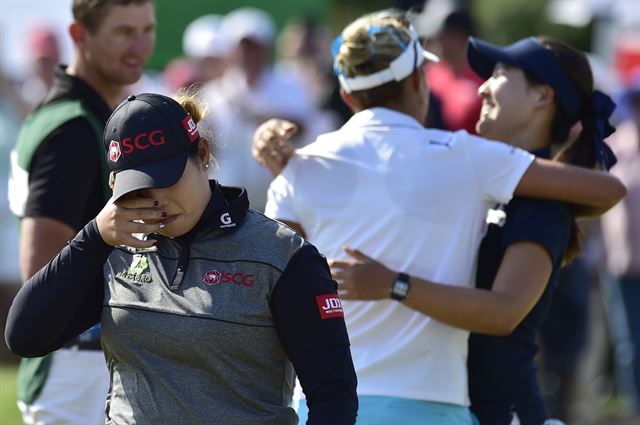 12일 캐나다 온타리오주 케임브리지 휘슬베어 골프장에서 막을 내린 미여자프로골프(LPGA) 투어 매뉴라이프 클래식에서 연장 접전 끝에 우승한 에리야 쭈타누깐(태국)이 눈물을 훔치고 있다. 함께 연장전을 벌인 전인지와 렉시 톰프슨(미국)이 뒤에서 서로 안으며 대화를 나누고 있다. 케임브리지=AP 연합뉴스