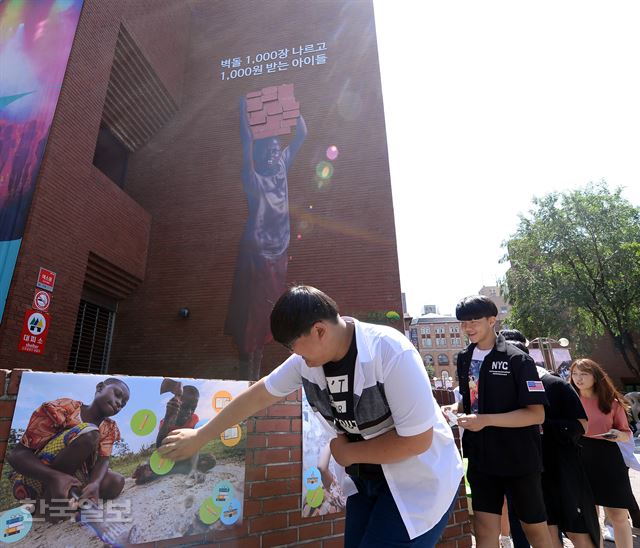 초록우산어린이재단 직원 및 자원봉사자들이 12일 ‘세계 아동노동 반대의 날’을 맞아 서울 동숭동 아르코예술극장 외벽에 아동노동의 현실을 알리는 사진을 전시하는 캠페인을 진행하고 있다. 배우한 기자