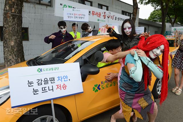 13일 서울 마포구 상암동 서부면허시험장에서 좀비 복장을 한 모델들이 도로교통공단의 '졸음운전 예방캠페인'을 소개하며 운전자를 끌고 가는 듯한 포즈를 취하고 있다. 신상순 선임기자