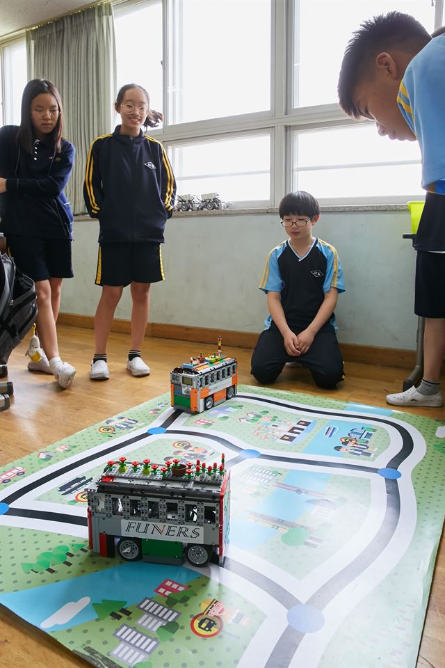 지난 8일 서울 금천구 세일중학교에서 진행된 소프트웨어 교육 프로그램 '코딩 지니어스' 수업에서 학생들이 레고를 조립해 만든 자율주행 버스가 움직이는 모습을 지켜보고 있다. LG CNS 제공