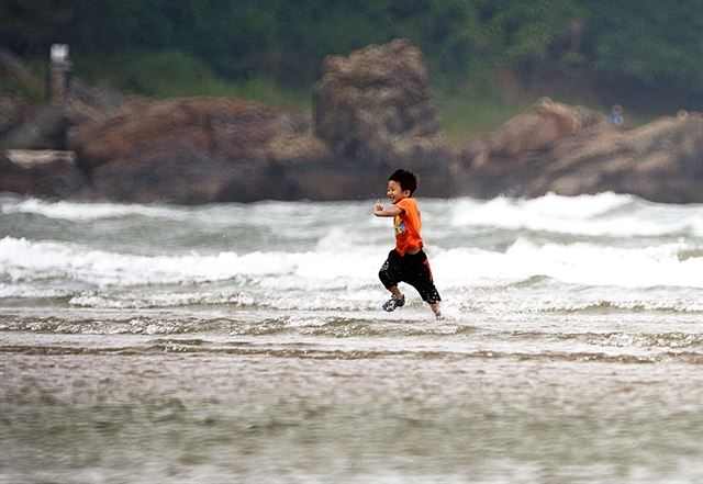 가족과 함께 부산 다대포 해수욕장을 찾은 한 어린이가 밀려오는 파도에 더위를 식히고 있다.