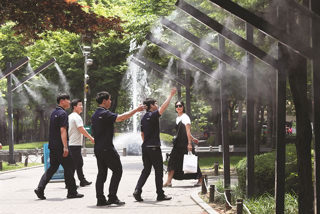 (대구=연합뉴스) 폭염이 이어진 19일 대구시 중구 동성로 2·28 기념공원에 설치된 쿨링포그 아래로 시민이 지나가고 있다. 쿨링포그 시스템은 정수된 물을 안개와 같은 미세입자로 분사해 주변 온도를 낮추는 냉방장치다. 2017.6.19