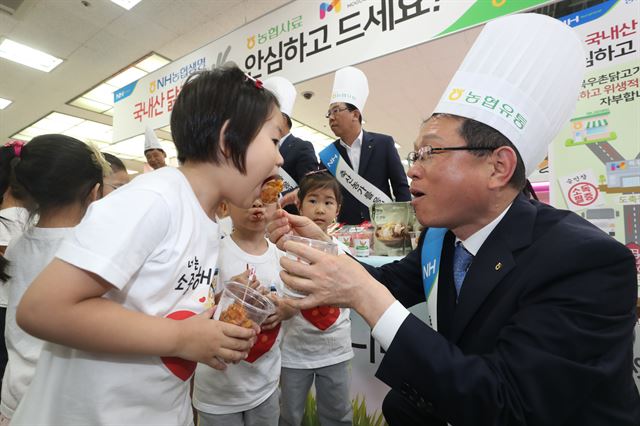 김원석(오른쪽) 농협경제지주 대표가 19일 서울 서초구 농협하나로마트 양재점에서 열린 닭고기 상생마케팅 후원금 전달식에서 어린이 고객들에게 치킨을 나눠주고 있다. 농협중앙회 제공