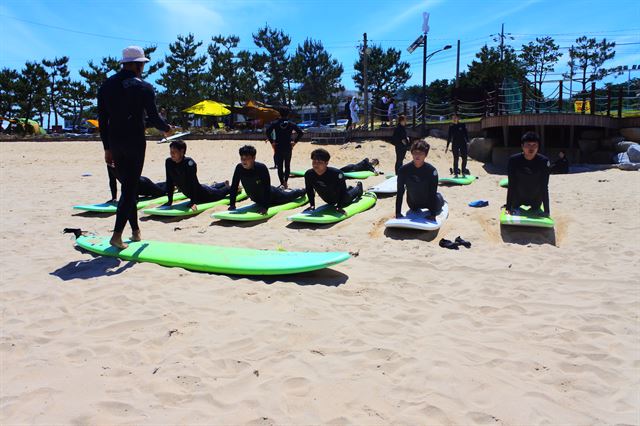 강원 양양군 죽도해변에서 서핑 입문자들이 입수 전 전문강사로부터 교육을 받고 있다.