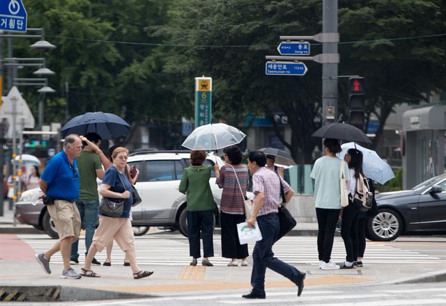 지난 24일 가랑비가 내린 서울 세종로 사거리에서 사람들이 우산을 쓰고 지나가고 있다. 연합뉴스