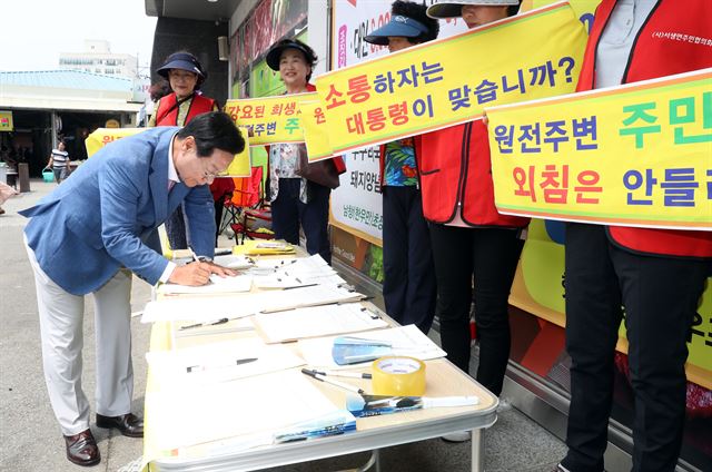 정부가 신고리 5·6호기 공사를 일시중단하고, 공론화 작업을 벌이겠다고 발표한 가운데 28일 오후 울산시 울주군 온양읍 남창옹기종기시장에서 신장열 울주군수가 '신고리 원전 5·6호기 건설 중단 반대' 서명을 하고 있다. 2017.6.28 울산=연합뉴스