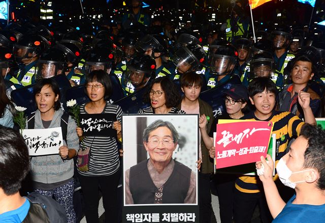 지난해 10월 서울 종로구 대학로에서 열린 '백남기 농민 추모대회' 참가자들이 백남기 농민 사진을 들여보이고 있다. 뉴시스