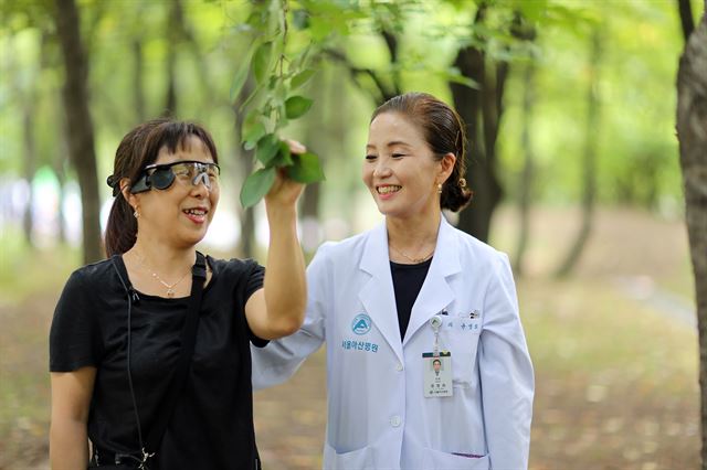 윤영희(오늘쪽) 서울아산병원 안과 교수와 망막이식 수술을 받은 이화정씨가 나뭇잎을 바라보면 얘기를 나누고 있다. 서울아산병원 제공