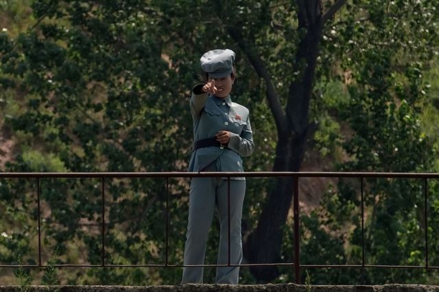 북한이 대륙간 탄도 미사일을 발사한 지 하루가 지난 5일 중국 국경도시 단둥 맞은편 신의주 부근 압록강변에서 보초를 서고 있는 한 북한 여군이 맞은편을 가르키고 있다. AFP 연합뉴스