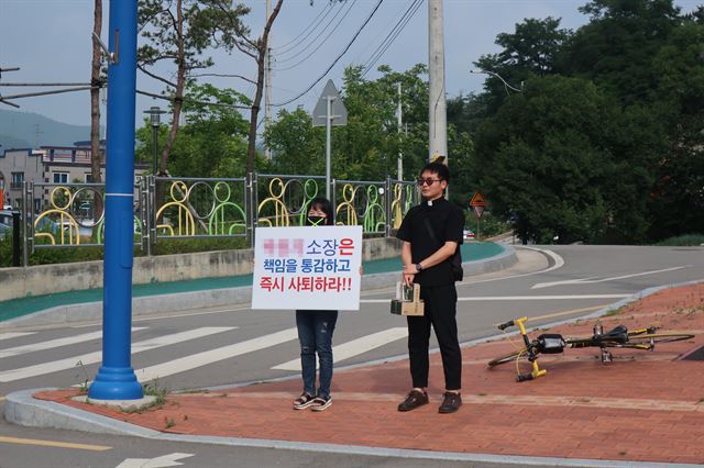 군위군자원봉사센터 직원이 5일 센터 앞에서 1인 시위를 하는 가운데 인근 성당 성직자가 격려하고 있다. 권성우기자 ksw1617@hankookilbo.com