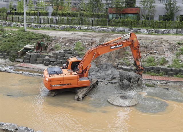 지난 17일 오전 청주시 흥덕구 석남천에서 포크레인이 폭우로 떠내려온 펄을 퍼내고 있다. 연합뉴스