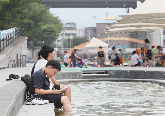 서울 송파구 성내천 물놀이장에서 한 학생이 물에 발을 담근 채 공부를 하고 있다. 연합뉴스