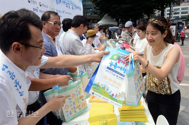 농협중앙회,농식품부 등 관계자들이 20일 오전 서울 광화문 동화면세점 앞에서 여름 휴가 농촌ㆍ산촌ㆍ어촌에서 보내기 캠페인을 진행, 시민들에게 홍보 책자와 지도, 부채 등을 전달하고 있다.고영권기자youngkoh@hankookilbo.com