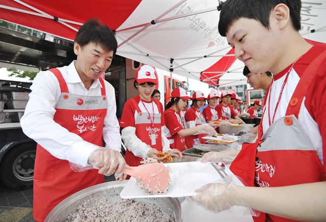 채종진(왼쪽) BC카드 사장이 '사랑나눔축제'에서 빨간밥차 봉사자들과 함께 식사 배식을 하고 있다. BC카드는 사랑나눔 축제를 통해 시즌별로 김장김치, 보온용품, 제철과일 등의 선물과 문화공연, 법률 및 의료상담 등 서비스를 전달한다. BC카드 제공