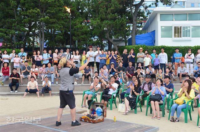 22일 오후 7시 부산 해운대해수욕장 ‘해운대 해변 라디오ㆍ북 카페’에서 ‘해변 라디오’가 열려 많은 관광객들이 마술공연을 관람하고 있다.