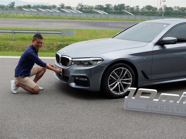 BMW 520d 딩골핑 에디션 출고식. 직접 번호판을 차에 달고 포즈를 취하며 활짝 웃고 있다