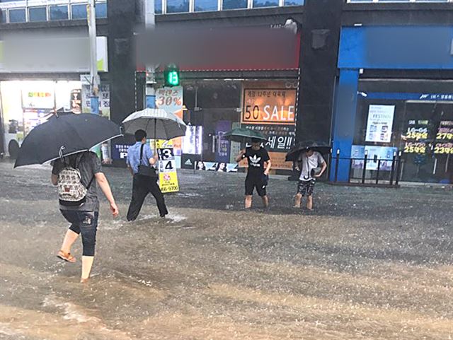 지난 23일 오전 인천광역시 남동구 만수동 인근 횡단보도에서 시민들이 폭우로 인해 잠긴 횡단보도를 건너고 있다. 뉴스1