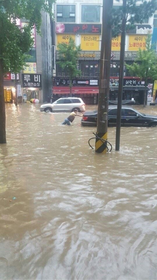 지난 23일 오전 내린 폭우로 호우경보가 발령된 경기 고양시 일산서구 탄현동의 한 도로에서 주민이 침수된 차량을 물 밖으로 빼내고 있다. 뉴시스