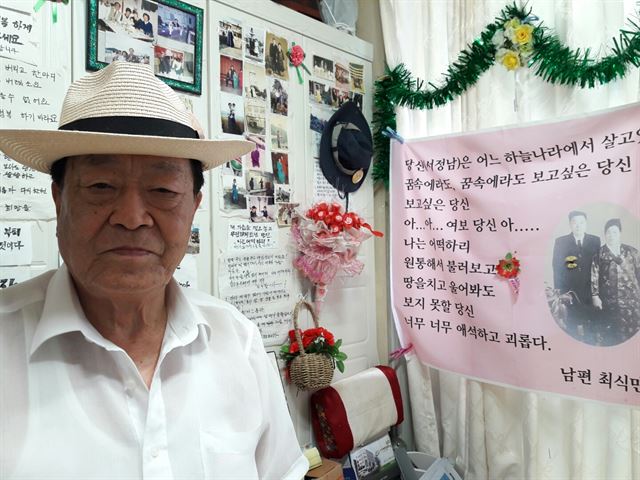 24일 오후 부산 사하구 자택 거실에 있는 최식만(87) 옹의 모습. 그 뒤로 2년 전 사별한 아내의 사진과 최 옹이 아내를 그리워하며 적은 글귀가 빼곡하다.