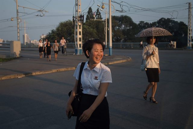 북한 평양에서 24일(현지시간) 한 여대생이 활짝 웃으며 길을 건너고 있다. AFP 연합뉴스