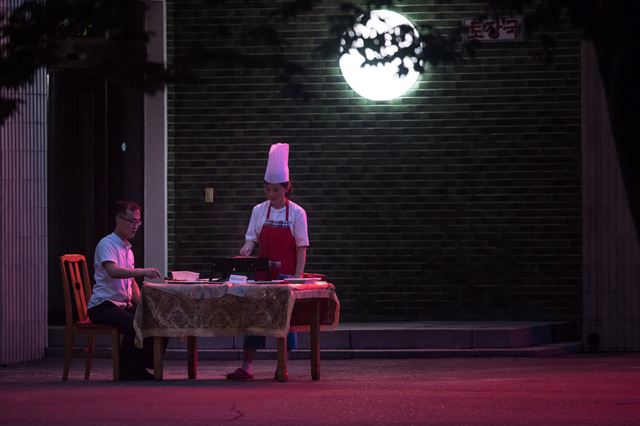 북한 평양의 한 레스토랑 앞에서 22일(현지시간) 한 손님이 음식을 먹고 있다. AFP 연합뉴스