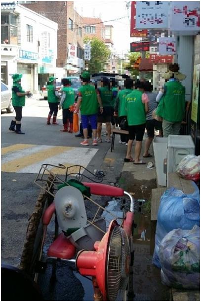 26일 오전 인천 남구 주안4동 한 상가 앞에 녹색 조끼를 입은 모 단체 회원들이 모여 있다. 시ㆍ구의원 등이 포함된 이들은 수해복구를 위해 모였지만 30분만에 철수했다. 독자 제공