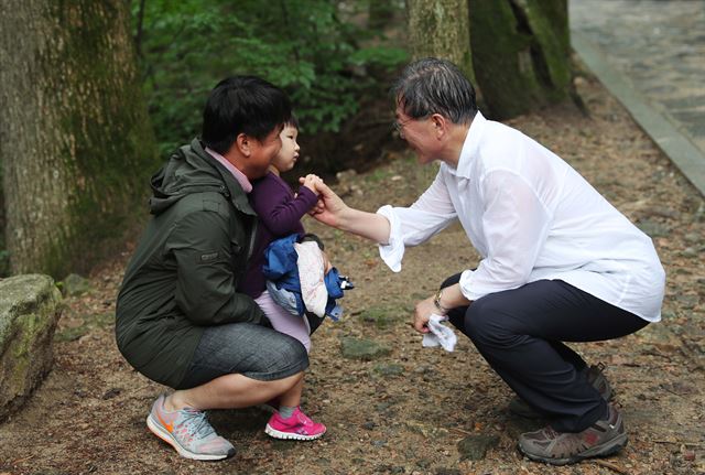 문재인 대통령이 휴가 중 오대산 상원사를 가는 길에 아버지와 같이 온 아이의 손을 잡으며 인사를 하고 있다. 청와대 제공