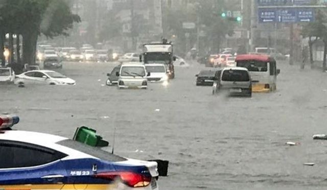 7월 23일 오전 인천 남구 간석동 도로 일부가 침수돼 차들이 힘겹게 통과하고 있다. 사진 제공=연합뉴스