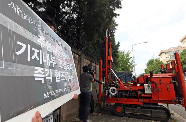 서울시 관계자가 9일 서울 용산구 주한미군 메인포스트 담장 밖에서 굴착기를 동원해 토양시료를 채취하고 있다. 이날 현장에는 용산미군기지온전히되찾기주민모임 회원들이 참석해 기지 내부 오염조사를 촉구했다. 연합뉴스