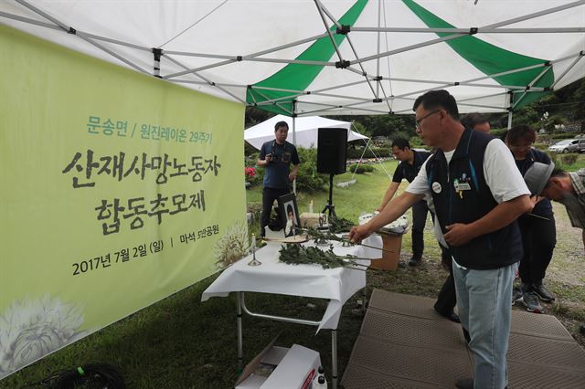 지난달 2일 경기도 남양주시 모란공원에서 열린 원진레이온 29주기 산재사망노동자 합동추모제에서 추모객이 헌화하고 있다. 연합뉴스