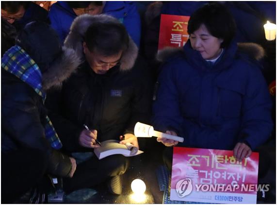 지난 2월 18일 오후 서울 광화문광장에서 열린 박근혜 대통령 탄핵 촉구 촛불집회에서 더불어민주당 추미애 대표가 시민들에게 사인을 해주는 문재인 전 대표에게 촛불로 빛을 비추어 주고 있다. 연합뉴스