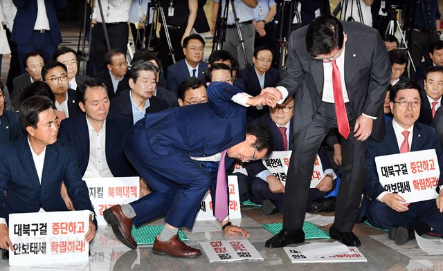 국회 보이콧 투쟁 중인 자유한국당이 8일 국회 본청에서 연 ‘보이스 오브 자유한국’ 발언대회에 참석한 홍준표(앞줄 왼쪽 두번째) 대표가 모두발언을 하려고 자리에서 일어서고 있다. 정우택 원내대표가 홍 대표의 손을 잡아 도움을 주고 있다. 배우한 기자