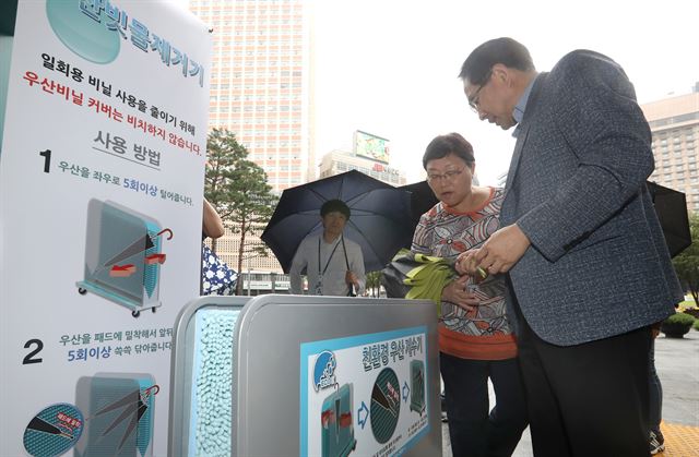 비가 내린 11일 오전 시민들이 서울시청 입구에 우산 비닐커버 대신 설치된 빗물 제거기를 이용하고 있다. 연합뉴스