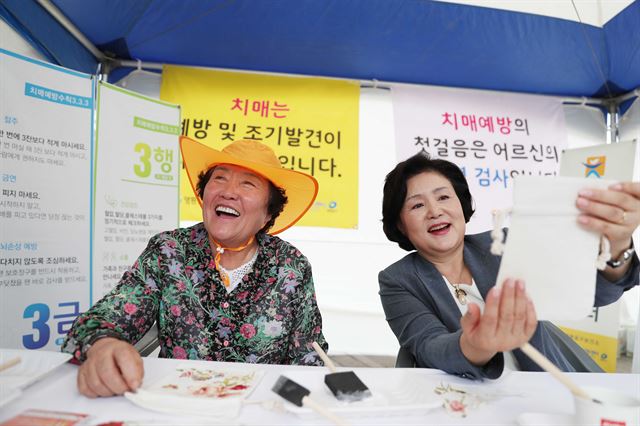 12일 오전 서울시청 광장에서 열린 서울시 주관 '치매극복의 날'기념행사에 참석한 김정숙여사가 어르신과 함께 기억주머니 만들기 체험하고 있다. 청와대제공