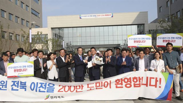 송하진 전북지사가 25일 한국식품연구원 신청사에서 박용곤 한국식품연구원장 및 임직원들에게 전북 이전을 환영하며 꽃다발을 전달하고 있다. 전북도청 제공