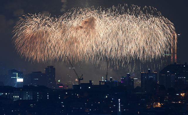 30일 오후 서울 용산구 건설 현장 타워크레인 뒤로 2017 서울불꽃축제 폭죽이 밤하늘을 수놓고 있다. 김주영기자 will@hankookilbo.com