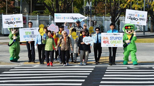 캠페인 참가자들이 ‘배려’ ‘양보’라고 적힌 손 피켓을 들고 횡단보도를 건너는 ‘보행 깃발 퍼포먼스’를 하고 있다.