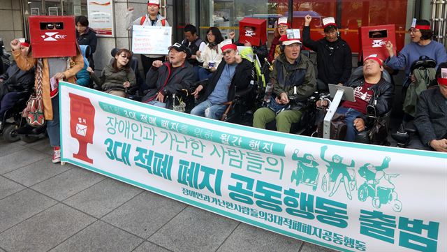 19일 오후 서울 종로구 광화문우체국 앞에서 열린 '장애인과 가난한 사람들의 3대 적폐 폐지 공동행동 출범 기자회견 및 청와대 엽서 전달을 위한 제1회 월간행진'에서 '3대적폐공동행동' 회원들이 "장애등급제, 부양의무자 기준, 장애인수용시설의 세 가지 적폐 완전히 폐지"구호를 외치고 있다. 연합뉴스