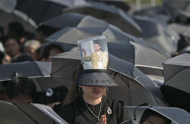 푸미폰 아둔야뎃 태국 전(前)국왕의 장례식 이틀째를 맞은 26일(현지시간) 방콕에서 검은 옷을 입고 검은 우산을 쓴 추모객들이 운구행렬을 바라보며 기도를 하고 있다.이날 검은 옷을 입은 수천명의 추모객들이 장례 행렬을 보기 위해 거리에서 밤을 지새웠으며 5천 600여 명의 군인들이 동원되어 국왕의 시신을 실은 길이 18m, 높이 11.1m의 금빛 '왕실전차' 를 화장장으로 인도했다. AP 연합뉴스