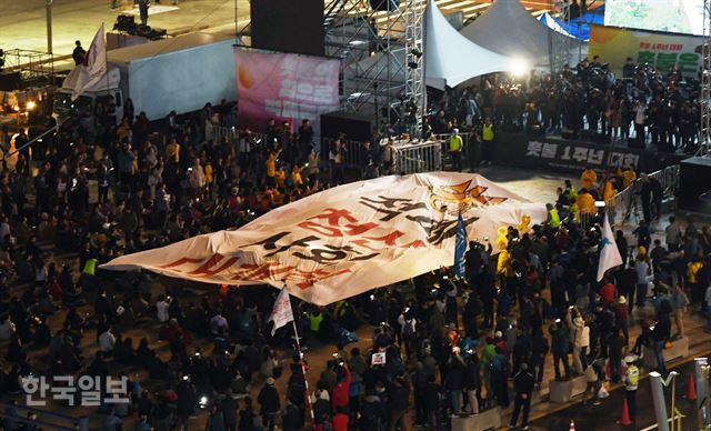 28일 저녁 서울 종로구 광화문 광장에서 박근혜정권퇴진 비상국민행동 기록기념위원회 주최로 열린 촛불 1주년 기념대회 ‘촛불은 계속된다’에 참석한 시민들이 <적폐청산 사회 대개혁>이라 적힌 현수막을 펼치고 있다. 홍인기 기자