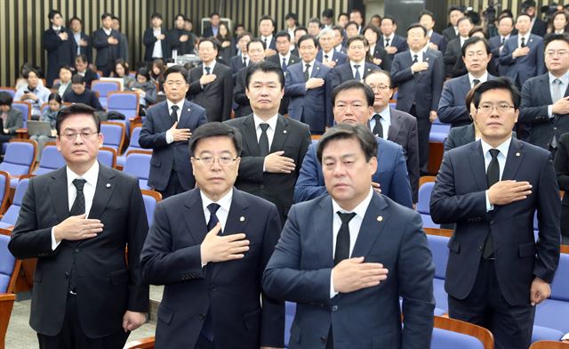 정우택(앞줄 맨 왼쪽) 원내대표, 김광림(왼쪽 두번째) 정책위의장, 김선동(맨 오른쪽) 원내수석부대표 등 자유한국당 의원들이 30일 국회에서 열린 의원총회에서 국기에 경례를 하고 있다. 의원들은 ‘공영방송 사망’의 의미로 검은 옷을 입었다. 연합뉴스